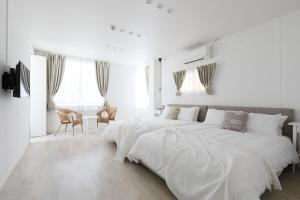 a white bedroom with a large bed with white sheets at Bijou Suites Sorriso in Osaka