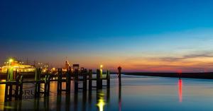 un muelle en el agua con una puesta de sol en el fondo en Short Stay De Rode Kers, en Harlingen