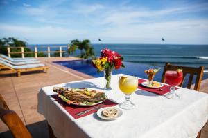 een tafel met een bord eten en uitzicht op de oceaan bij Hotel Los Mangos El Salvador in El Cuco