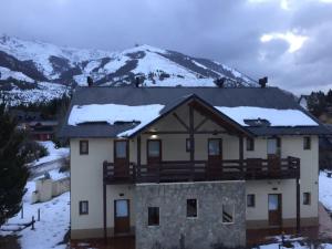 a house with snow on the roof with a mountain at Departamento Piedra del Condor in San Carlos de Bariloche