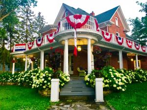 a house with a porch with an umbrella on it at 1000 Islands Bed and Breakfast-The Bulloch House in Gananoque