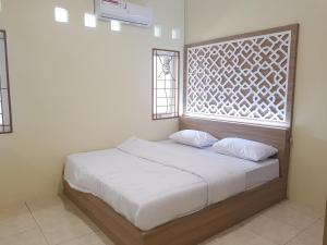 ein Bett mit zwei Kissen in einem Zimmer mit einem Fenster in der Unterkunft De Hanami Homestay in Cirebon