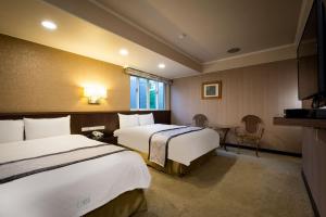 a hotel room with two beds and a table at Good Life Hotel - Shang Hwa in Taipei