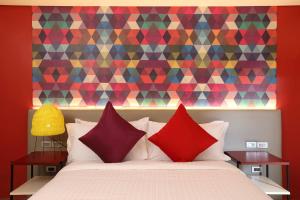 a bed with red pillows in front of a colorful wall at Lagùn Hotel in El Nido