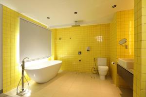 a yellow bathroom with a tub and a toilet at Lagùn Hotel in El Nido
