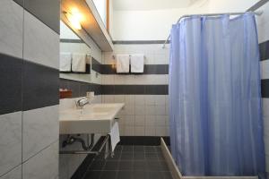 a bathroom with a sink and a blue shower curtain at Eri Hotel in Parikia