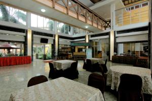 University Hotel في Kalasan: مطعم فيه طاولات وكراسي في الغرفة