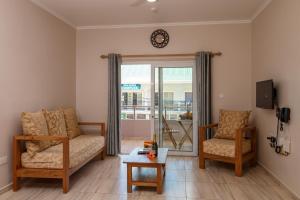 un soggiorno con 2 sedie, un tavolo e un orologio di Shanaz Beachside Retreat ad Anse Royale