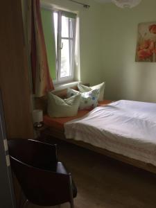 een slaapkamer met een bed, een raam en een stoel bij Fewo 2 Ferienwohnung Waren Müritz - Haus Buchen am Tiefwarensee - 2 Zi in Waren
