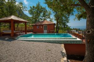 a swimming pool with a house and a tree at Harmonia Bungalows & Pool in Sveti Stefan