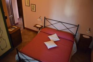 una camera con un letto rosso con due cuscini sopra di Agriturismo I Romiti a Castiglione del Lago