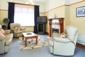 un soggiorno con sedie, TV e tavolo di Admiral Court Motel & Apartments a Invercargill