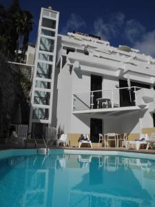 een zwembad voor een wit gebouw met een huis bij Apartamentos Los Mocanes in Puerto Rico de Gran Canaria