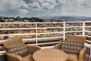 einen Balkon mit Stühlen und Blick auf einen Zug in der Unterkunft Leonardo Hotel Granada in Granada
