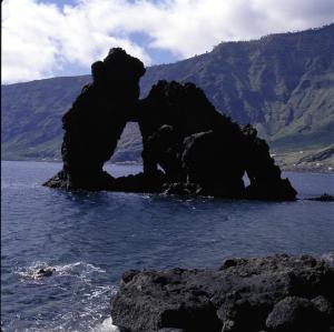 a rock in the water with mountains in the background at Parador de El Hierro in Las Casas