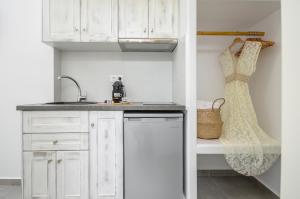 a kitchen with white cabinets and a dress hanging on a rack at 3 Wishes in Naxos Chora