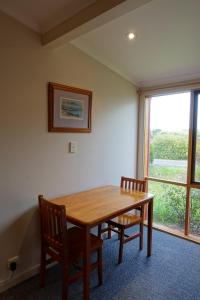 a dining room table with two chairs and a large window at Coal Creek Motel in Korumburra