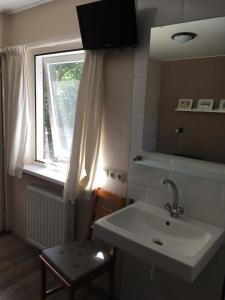 uma casa de banho com um lavatório, um espelho e uma janela em Bungalow Halfweg em Ballum