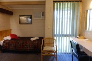 a room with a bed and a chair and a desk at Coal Creek Motel in Korumburra