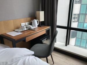 una camera da letto con scrivania e sedia accanto a una finestra di Honest & Warm Hotel a Taoyuan