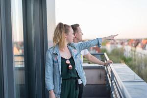 a man and a woman standing on a balcony looking at the city at Ku'Damm 101 Hotel in Berlin