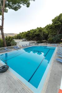 a large blue swimming pool with chairs and trees at Mina Apartments in Poros