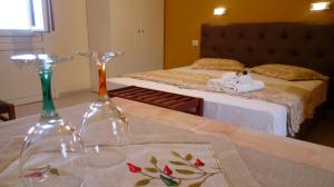 two wine glasses on a table with a bed at Studios Rania - Rania Studios & Apartments in Lassi