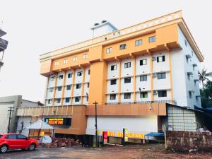 a building with a red car parked in front of it at Kalluvalappil Holiday Inn in Kāsaragod