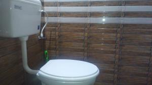 baño con aseo y pared de madera en Villa Vibes, en Chikmagalur