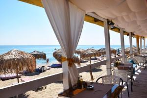 a beach with tables and straw umbrellas and the ocean at Helga Apartment in Obzor +18 photos