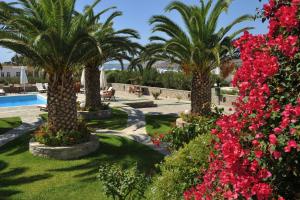 a garden with palm trees and flowers next to a swimming pool at Eri Hotel in Parikia