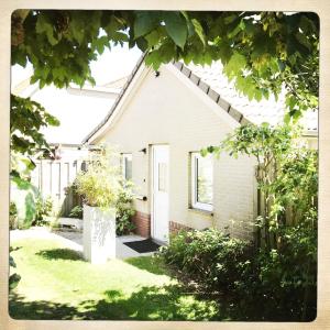 a small white house with a yard with grass at De Munnik in Camperduin