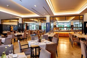 a dining room with tables and chairs and windows at Hotel am Badersee in Grainau