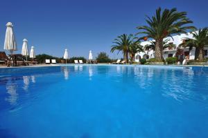 a large blue swimming pool with palm trees and umbrellas at Eri Hotel in Parikia