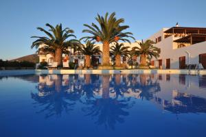 a pool with palm trees in front of a building at Eri Hotel in Parikia