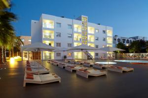 ein Hotel mit Tischen und Sonnenschirmen vor einem Gebäude in der Unterkunft Ibiza Sun Apartments in Playa d'en Bossa