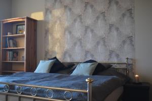 a bedroom with a blue bed with a wall at Apartament Park in Słupsk