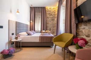 Schlafzimmer mit einem Bett, einem TV und einem Stuhl in der Unterkunft Boutique B&B Villa Faggioni in Cavtat