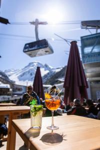 a wooden table with two drinks on a table with a mountain at Hôtel Alpina - Swiss Ski & Bike Lodge Grimentz in Grimentz