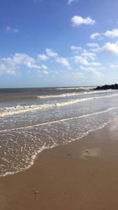 a beach with waves coming in from the ocean at Immaculately Presented Detached Family Chalet - 5 mins to beach, nr Great Yarmouth & Norfolk Broads in Great Yarmouth
