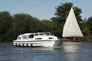 a white boat and a small sailboat on the water at Immaculately Presented Detached Family Chalet - 5 mins to beach, nr Great Yarmouth & Norfolk Broads in Great Yarmouth
