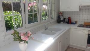 una cocina blanca con fregadero y un jarrón con flores en Le Memagne, en Florenville