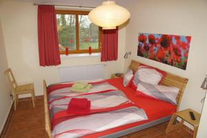 a bedroom with a bed with a red comforter at Ostetal in Hemmoor