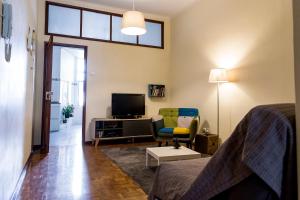 a bedroom with a bed and a chair and a television at Downtown Shelter - Casa da Praça in Aveiro