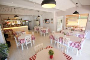 un restaurante con mesas y sillas blancas y una barra en Beva Hotel, en Sarandë