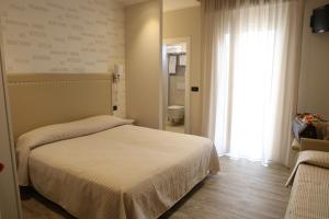 リミニにあるHotel Piccinelliのベッドルーム(白いベッド1台、窓付)