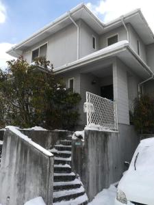 una casa con nieve en las escaleras delante de ella en Jukichi Owada Residence en Sendai