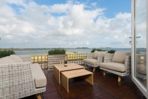 a patio with chairs and a table and a view of the water at Appartement Zilte Lucht in Wilhelminadorp