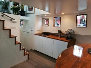 a kitchen with a staircase and a table with a fan at houseboat Rose in Amsterdam