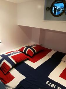 a bed with a red white and blue comforter and a mirror at houseboat Rose in Amsterdam